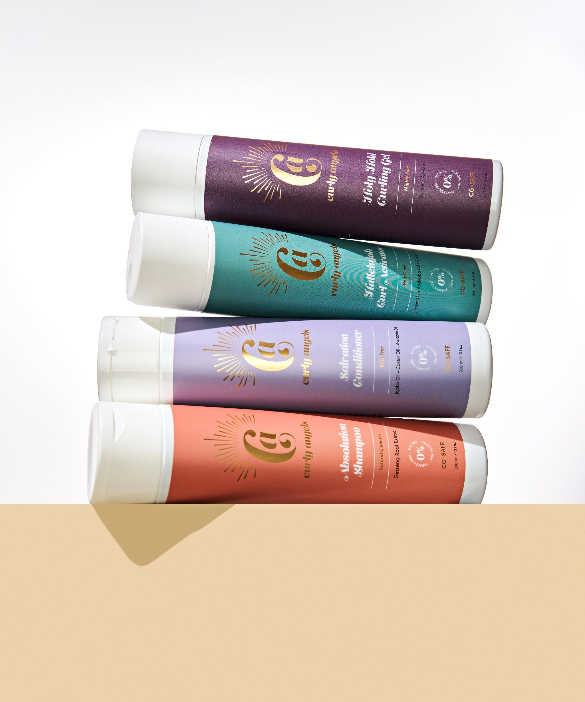 CURLY ANGELS strong hold set absolution shampoo salvation conditioner hallelujah curl activator holy hold curling gel bottles stacked on a biege platform -vegan -cruelty-free -organic