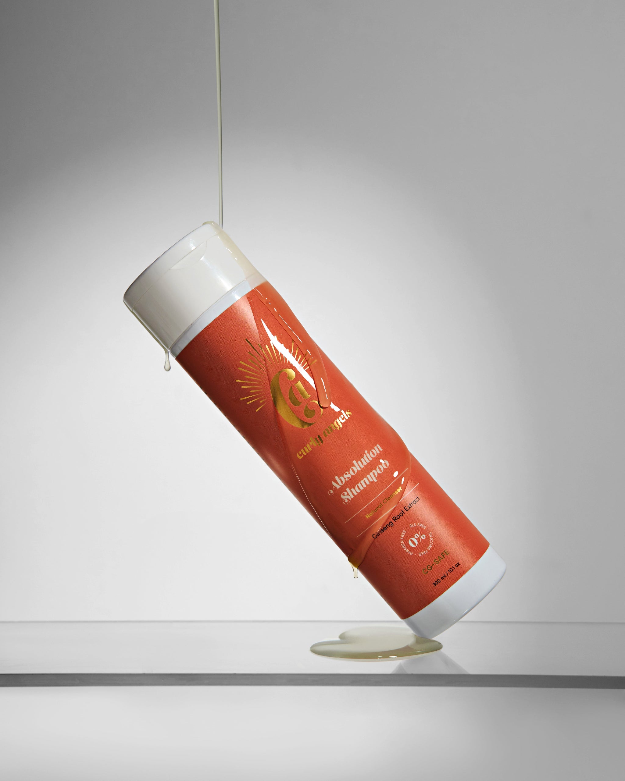 Curly Angels Absolution Shampoo, tilted against glass with honey poured over - vegan haircare, cruelty-free